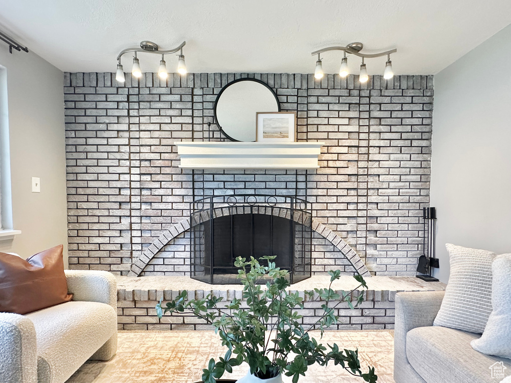 Living area with rail lighting, a brick fireplace, and brick wall