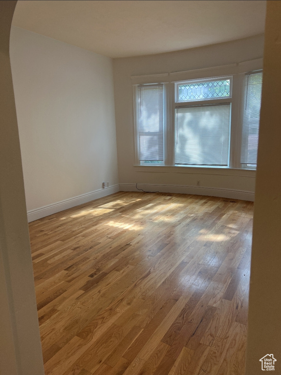 Unfurnished room with wood finished floors, baseboards, and arched walkways