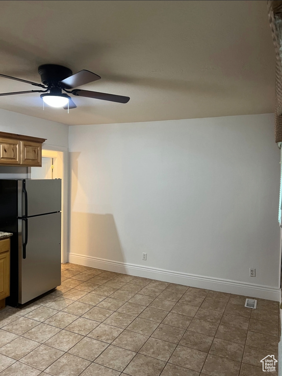 Kitchen featuring freestanding refrigerator, a ceiling fan, baseboards, and light tile patterned floors