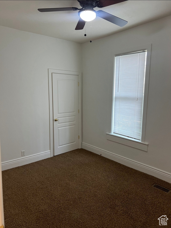Carpeted empty room with a ceiling fan and baseboards