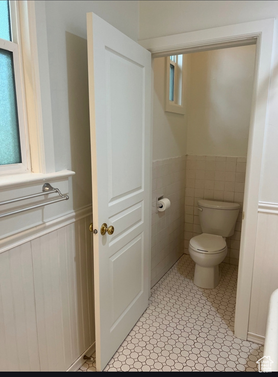 Bathroom featuring a wainscoted wall and toilet