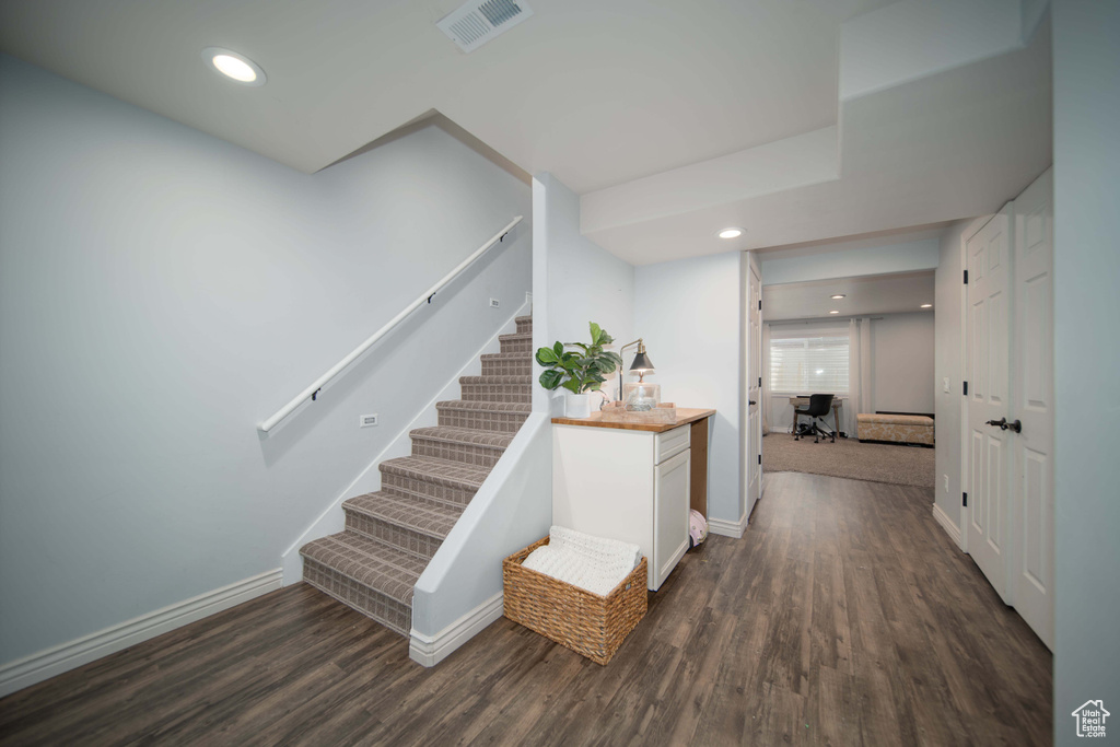 Hall featuring stairs, dark wood-style flooring, baseboards, and recessed lighting