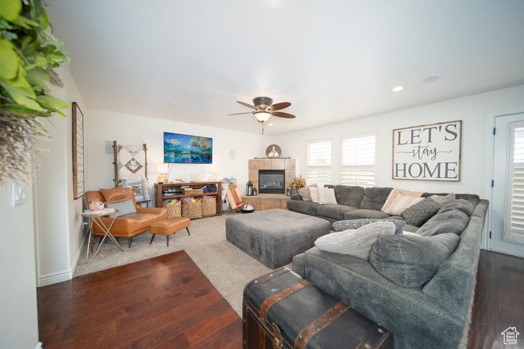 Living area with a ceiling fan, plenty of natural light, dark wood-type flooring, a tiled fireplace, and recessed lighting