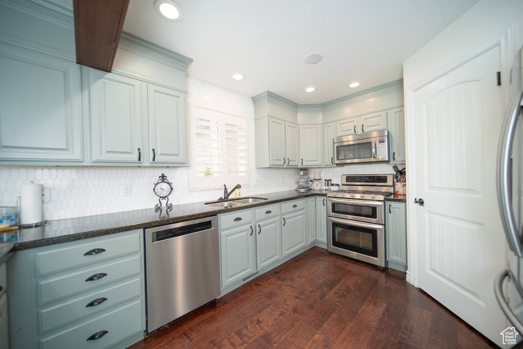 Kitchen featuring stainless steel appliances, a sink, tasteful backsplash, dark wood finished floors, and recessed lighting