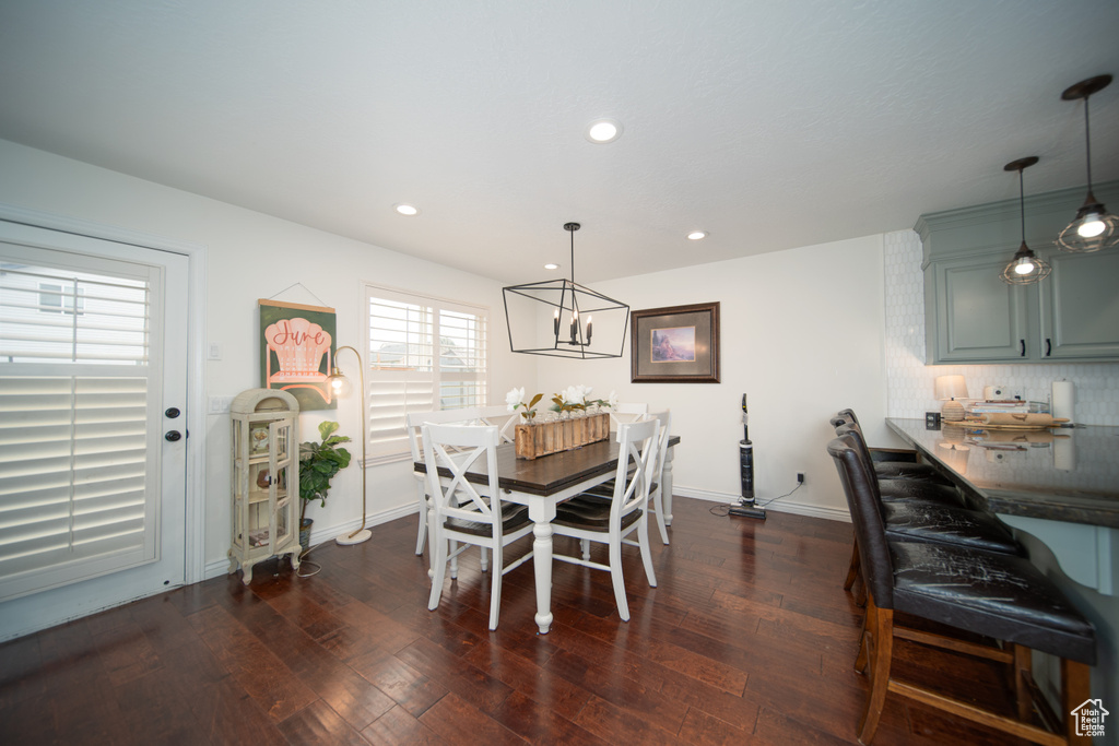 Dining space with dark wood finished floors, recessed lighting, baseboards, and a chandelier