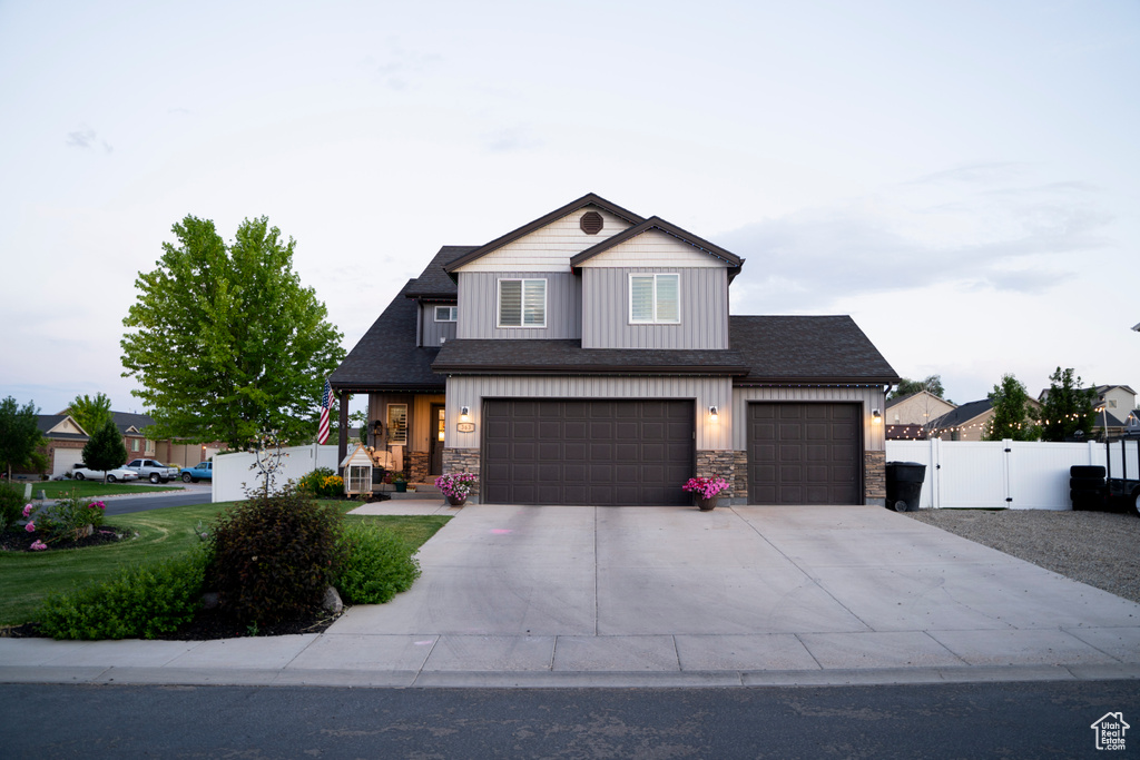 View of front facade with stone siding, a gate, driveway, and an attached garage