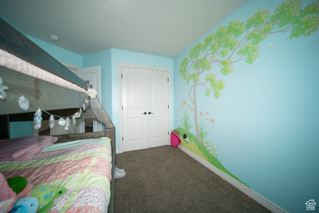 Bedroom featuring a closet, dark carpet, and baseboards