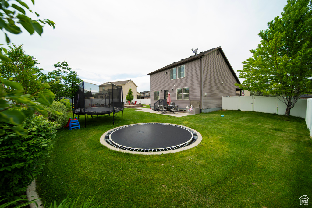 Rear view of property with a trampoline and a patio