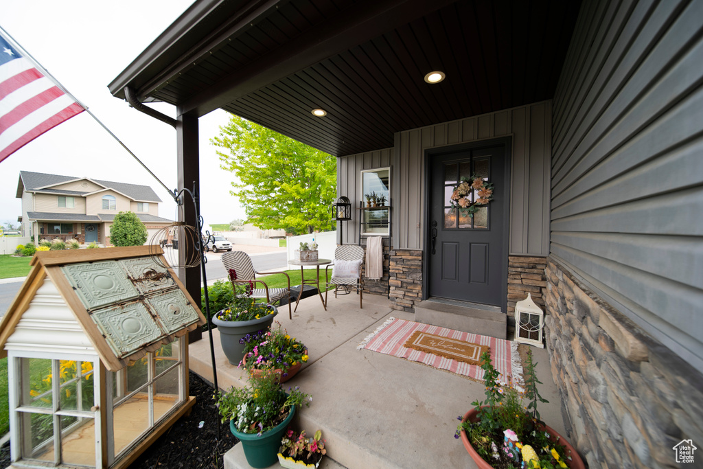 View of exterior entry with a porch, board and batten siding, and stone siding