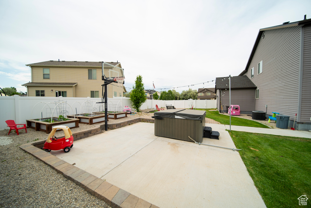 View of patio / terrace with a hot tub, a garden, and central air condition unit