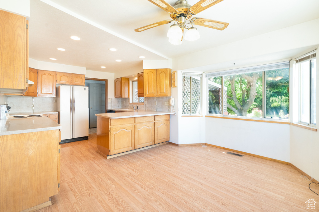 Kitchen with white appliances, light wood finished floors, baseboards, light countertops, and recessed lighting