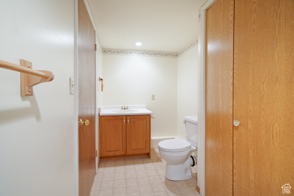 Half bathroom featuring toilet, vanity, and tile patterned floors