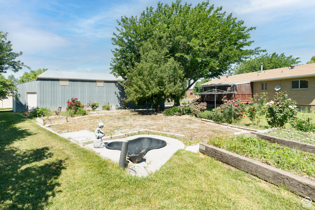View of green lawn featuring an outbuilding and a garden