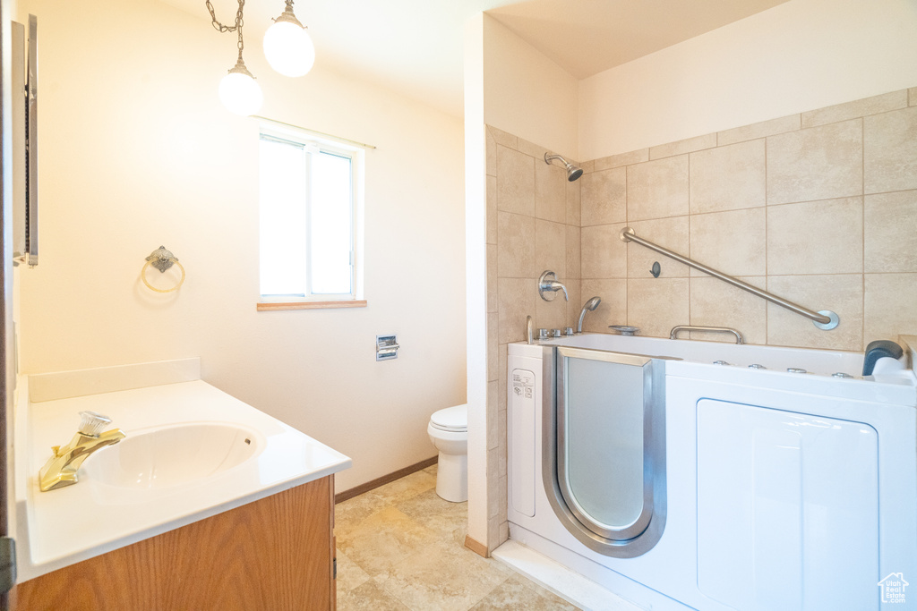 Bathroom with washer / clothes dryer, vanity, toilet, and baseboards