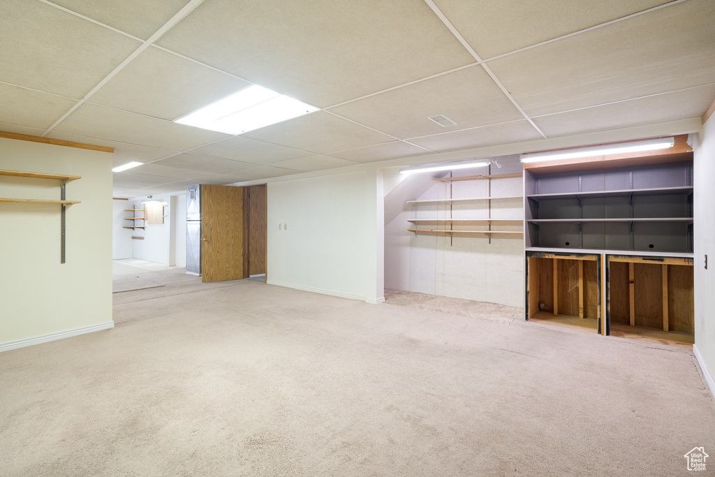 Finished basement with a paneled ceiling, carpet, and baseboards