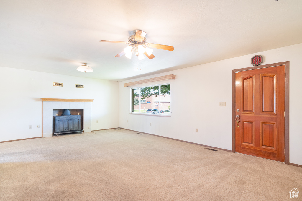 Unfurnished living room with a ceiling fan, carpet flooring, and baseboards