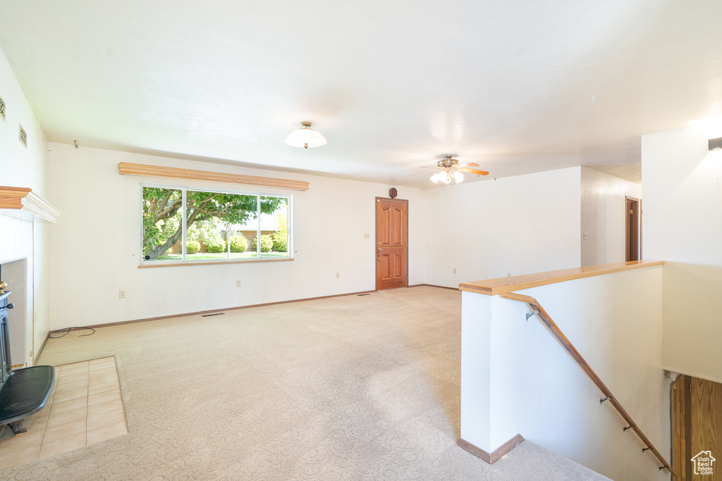Unfurnished living room with a ceiling fan, light colored carpet, and baseboards