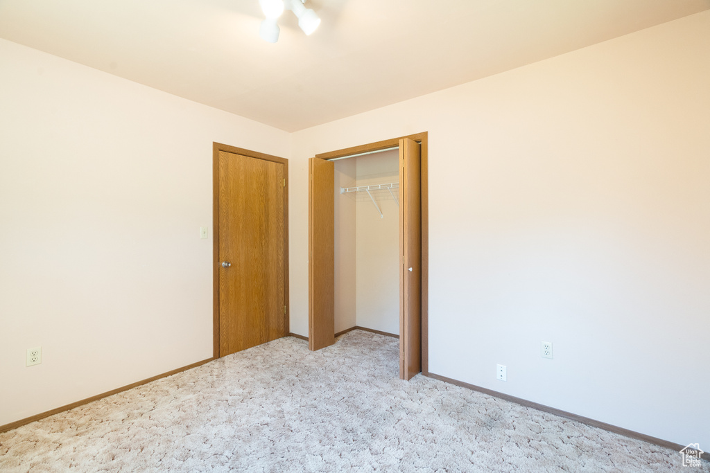 Unfurnished bedroom featuring light colored carpet, baseboards, and a closet
