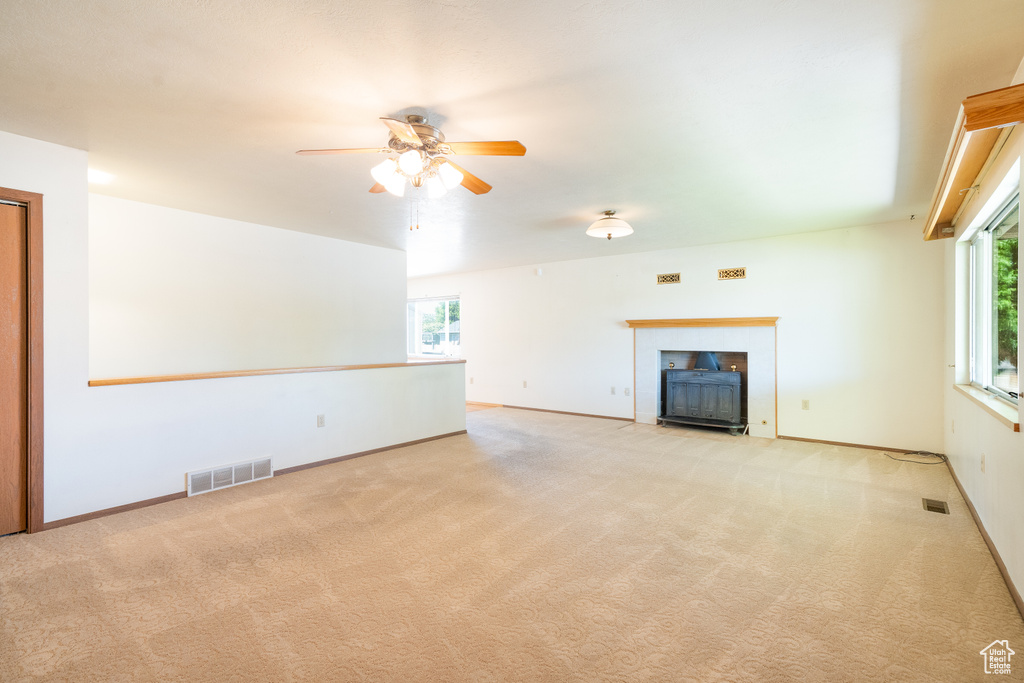 Unfurnished living room with a fireplace with flush hearth, healthy amount of natural light, and carpet flooring