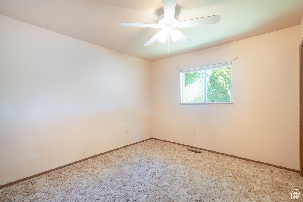 Spare room featuring ceiling fan, baseboards, and light carpet