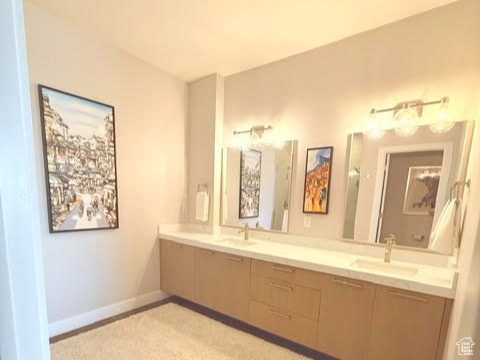 Bathroom with double vanity, baseboards, and tile patterned flooring