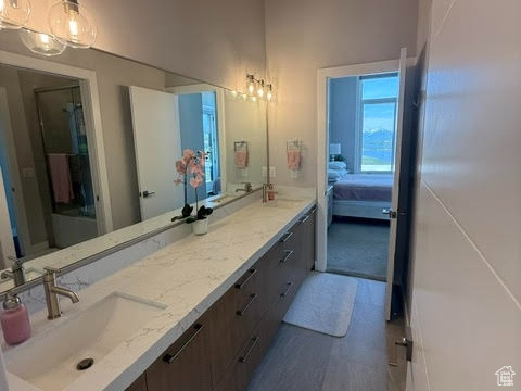 Full bathroom featuring a high ceiling, double vanity, ensuite bath, and wood finished floors