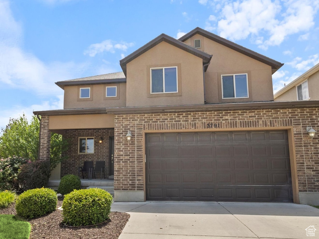 Traditional-style home with brick siding, concrete driveway, an attached garage, and stucco siding