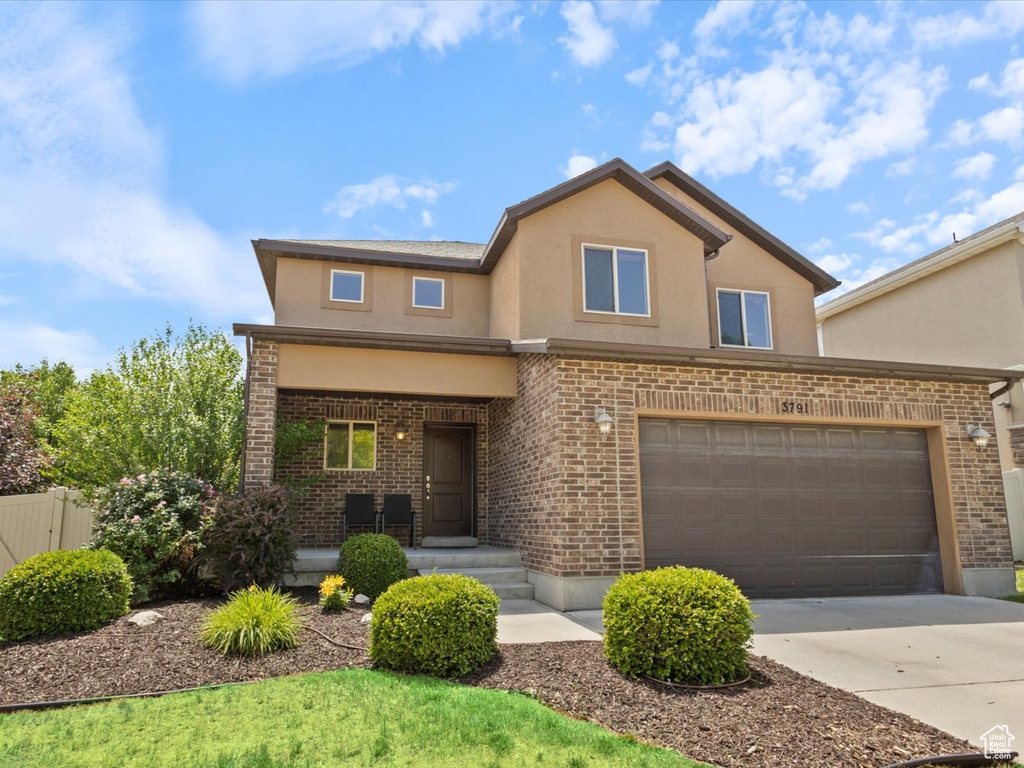 Traditional-style home with brick siding, driveway, and stucco siding