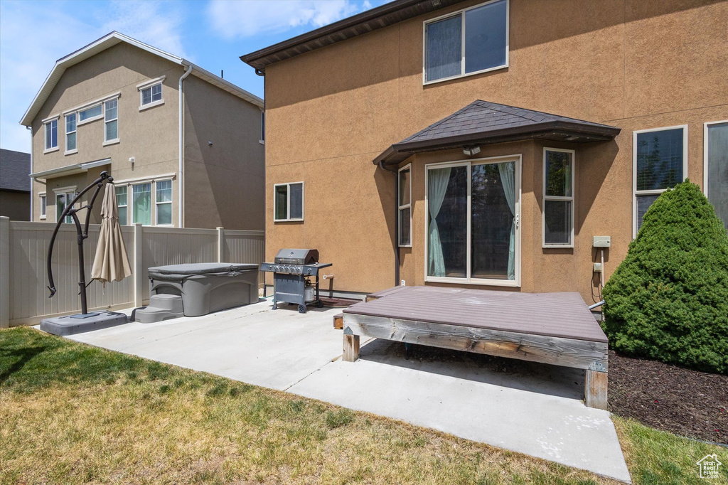 Back of house featuring stucco siding, a patio, a wooden deck, and a hot tub