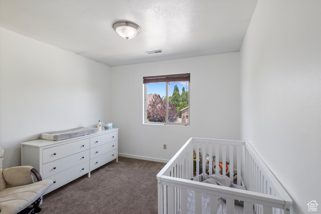 Bedroom with carpet and a crib