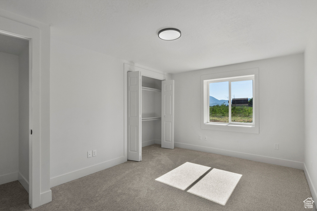 Unfurnished bedroom featuring carpet flooring, a closet, and baseboards