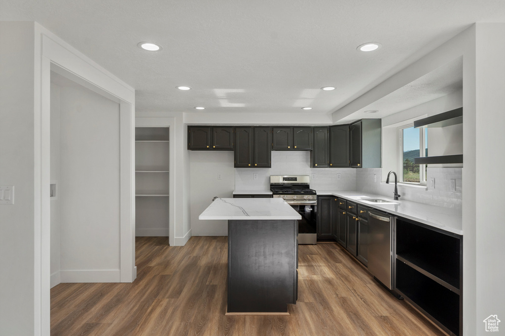 Kitchen featuring appliances with stainless steel finishes, a sink, dark wood finished floors, recessed lighting, and tasteful backsplash