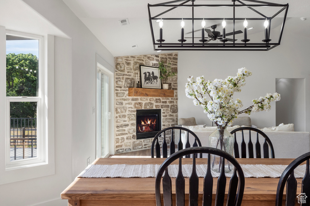 Dining space featuring lofted ceiling, a fireplace, a chandelier, and wood finished floors