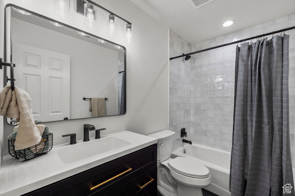 Bathroom featuring toilet, vanity, and shower / tub combo with curtain