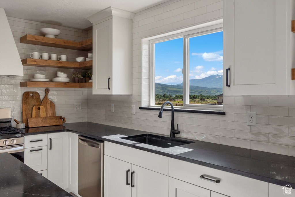 Kitchen featuring stainless steel appliances, a sink, a mountain view, white cabinets, and decorative backsplash