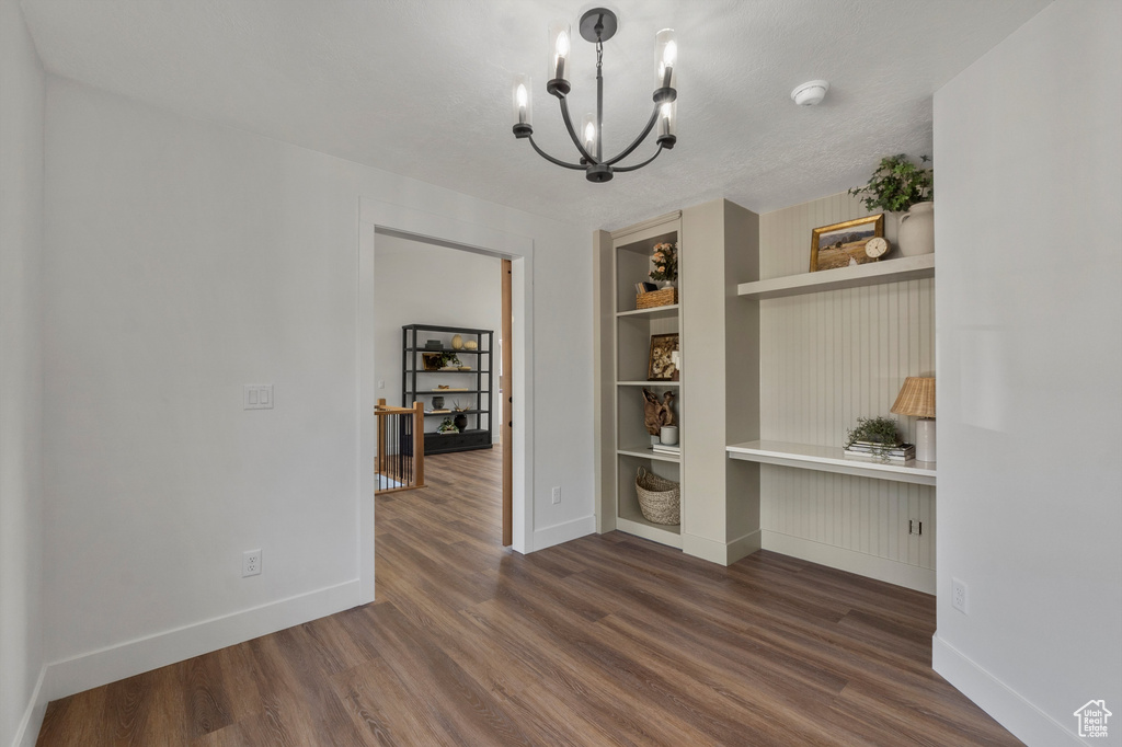 Unfurnished dining area featuring a chandelier, dark wood-style floors, baseboards, and built in features