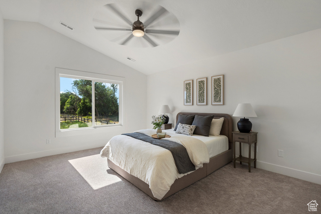 Carpeted bedroom featuring lofted ceiling, baseboards, and ceiling fan