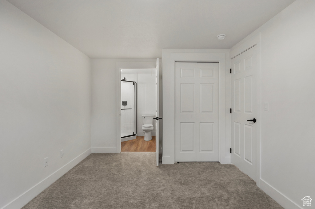 Unfurnished bedroom featuring carpet, baseboards, ensuite bathroom, and a closet