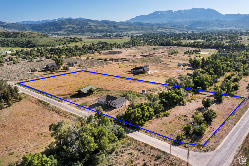 Aerial view of sparsely populated area with a mountainous background and property parcel outlined