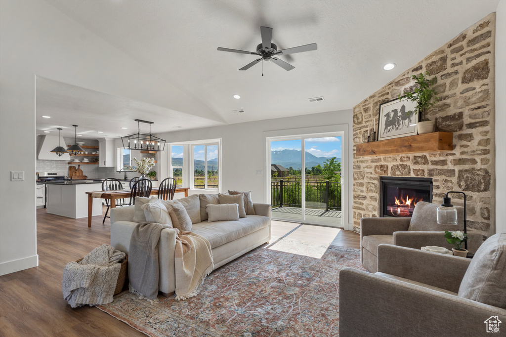 Living area featuring wood finished floors, a fireplace, lofted ceiling, a ceiling fan, and recessed lighting
