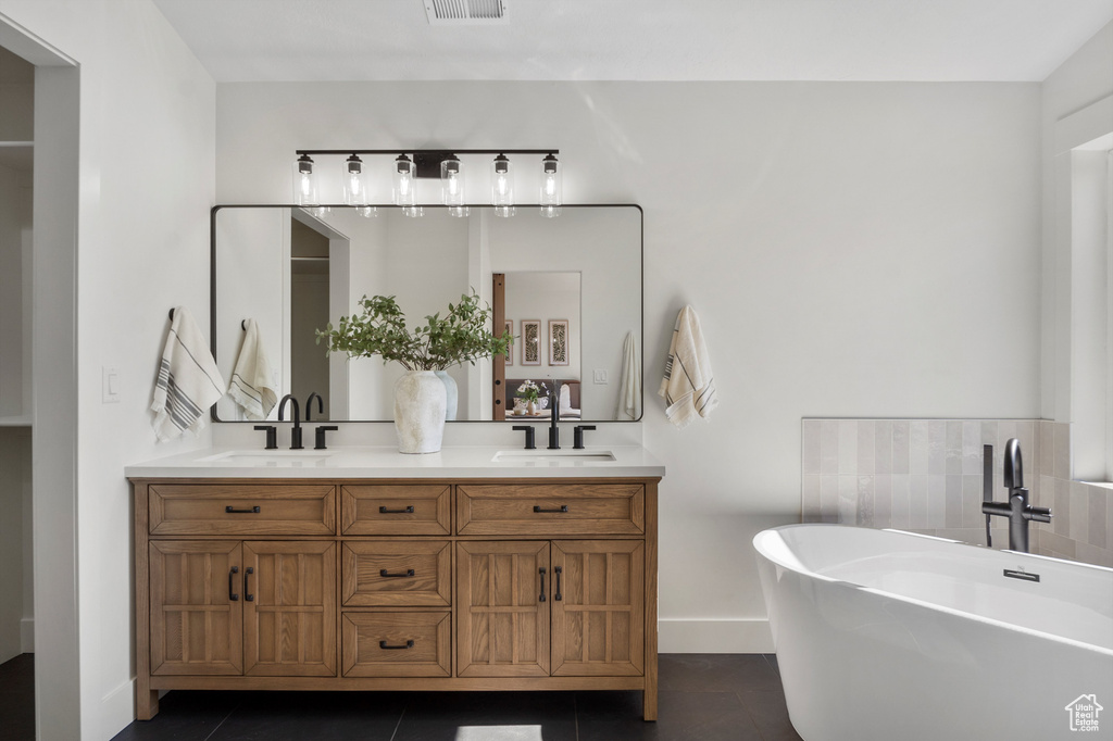 Full bath featuring double vanity, a freestanding tub, tile patterned flooring, and baseboards