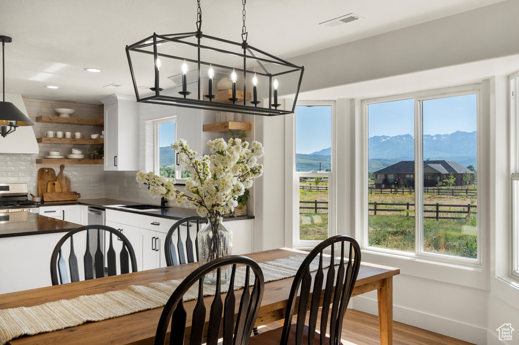 Dining room with a mountain view, wood finished floors, a chandelier, baseboards, and recessed lighting