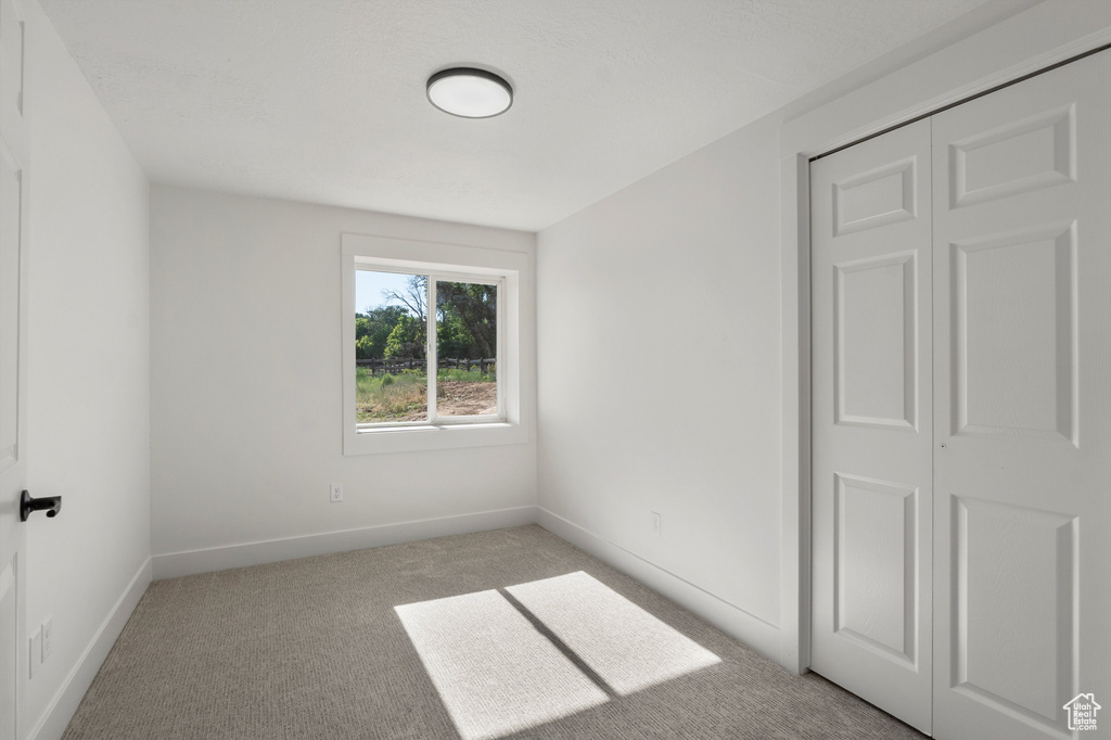 Empty room featuring light colored carpet and baseboards