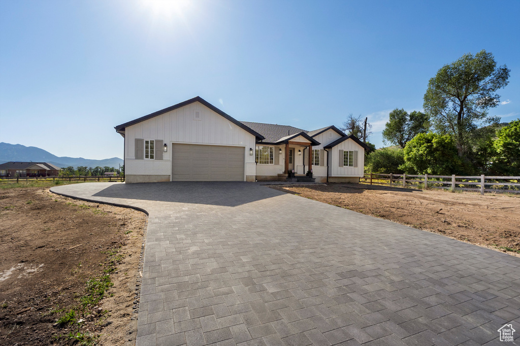 View of front of house featuring an attached garage, decorative driveway, board and batten siding, and a mountain view