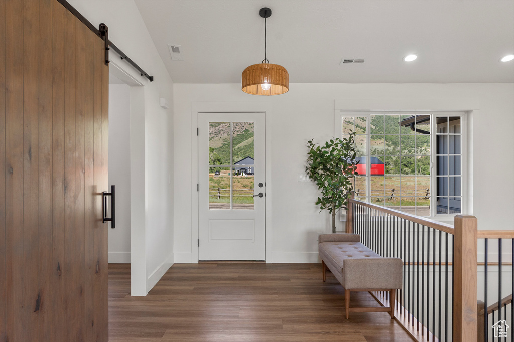 Foyer featuring a barn door, wood finished floors, plenty of natural light, baseboards, and recessed lighting