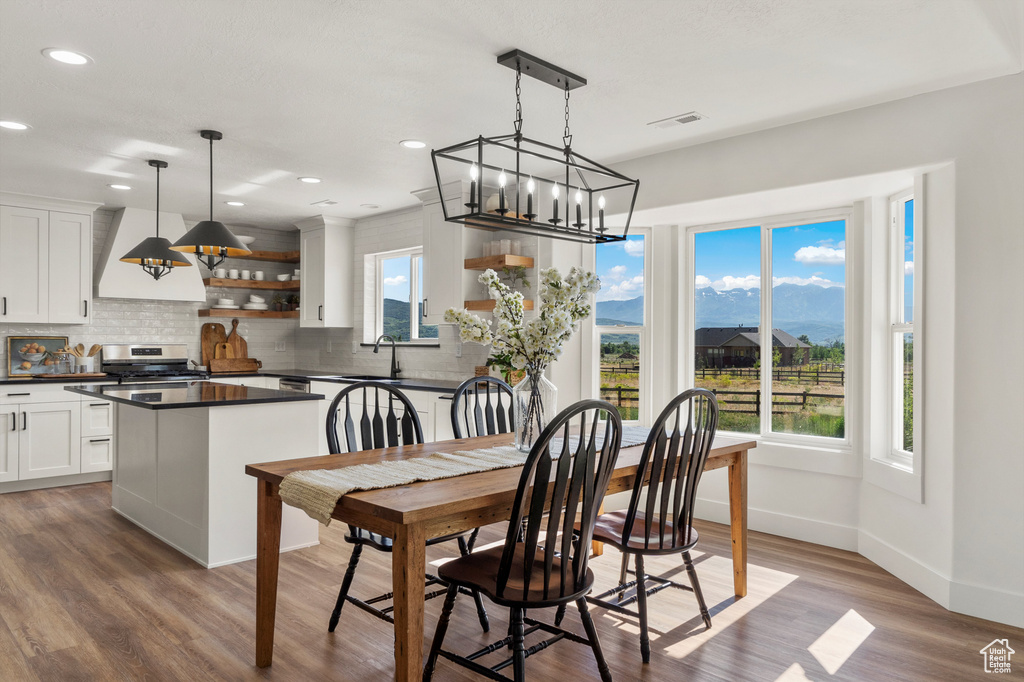 Dining room featuring a chandelier, light wood-type flooring, baseboards, recessed lighting, and a mountain view