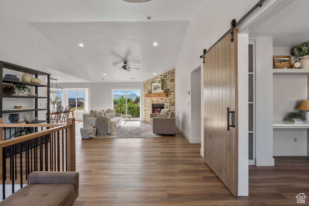 Living area with vaulted ceiling, a barn door, ceiling fan, wood finished floors, and recessed lighting