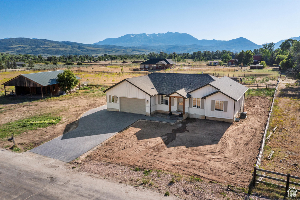 View of front of property with asphalt driveway, an attached garage, a view of countryside, and a mountain view