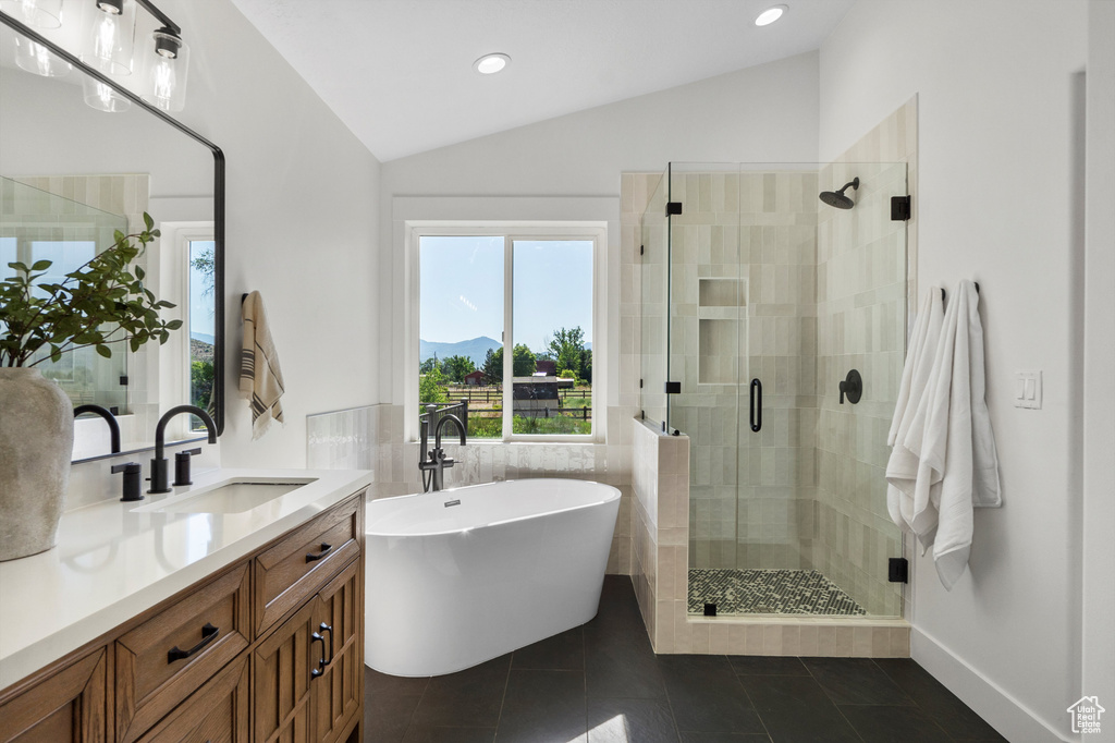 Bathroom featuring lofted ceiling, a stall shower, vanity, a freestanding tub, and tile patterned floors