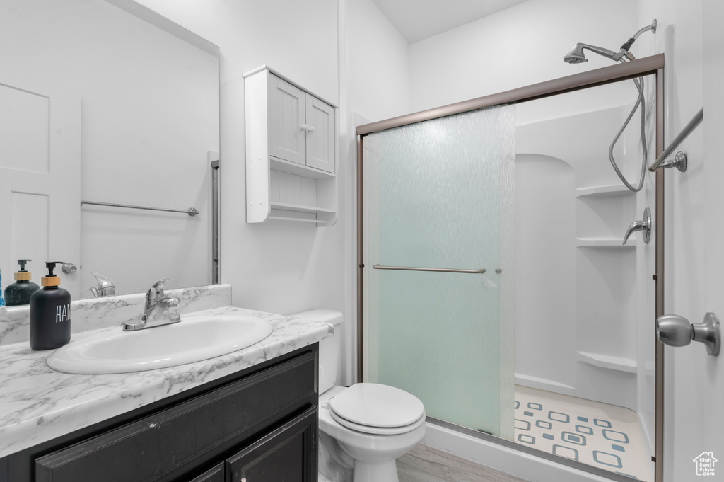 Bathroom featuring a stall shower, vanity, and toilet
